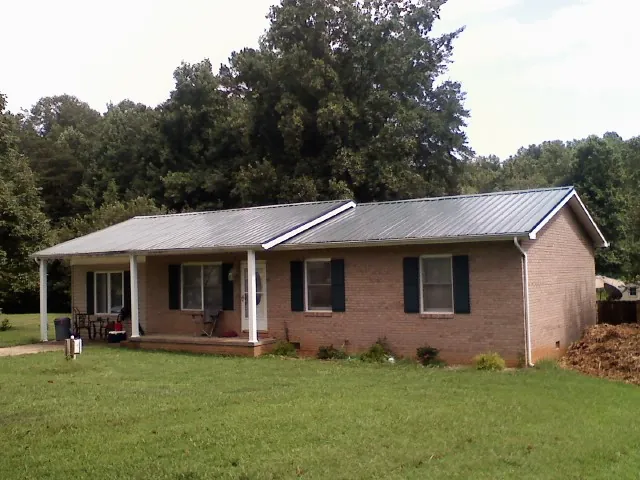 Gray metal roof on a brick ranch house with a side carport in Milford